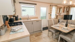 Cocina compacta con lavamanos, estufa y comedor con sillas y una mesa dispuesta para dos.