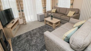 Una sala de estar amoblada con sofá, mesa de centro, televisor y cortinas.