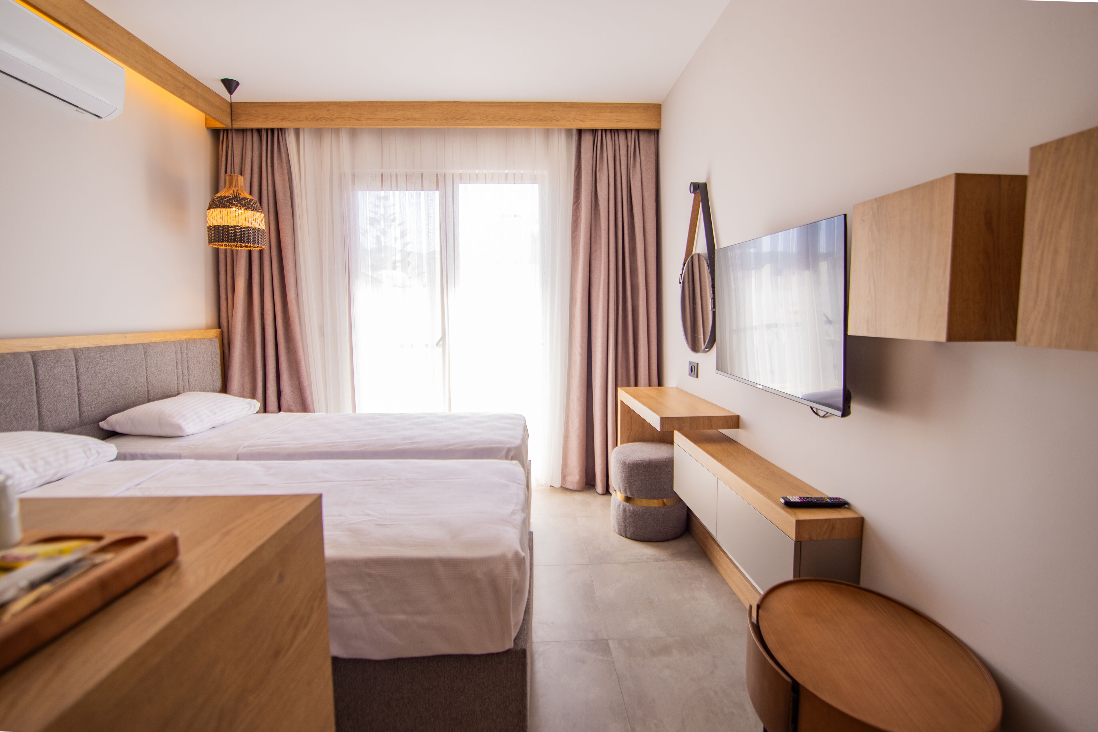 A hotel room with two beds, a TV, a desk, and a chair.