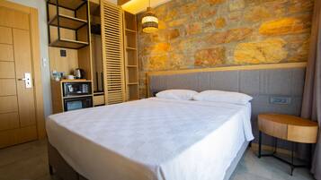 Un dormitorio con una cama grande, un armario empotrado, una mesita pequeña y una pared de piedra.