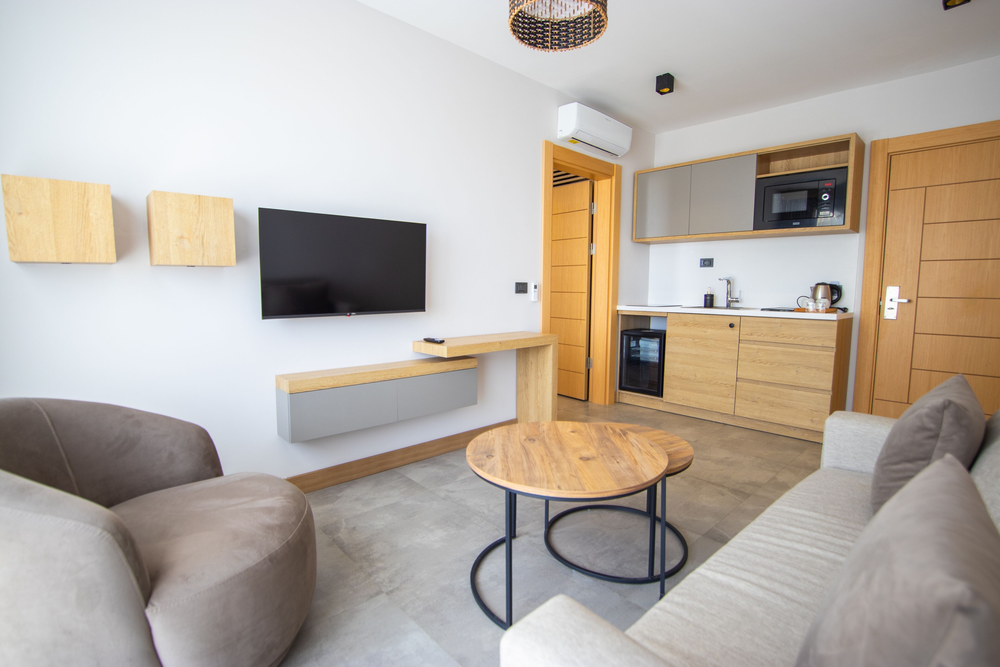 A modern living room with a flat-screen TV, wooden furniture, and a small round table.