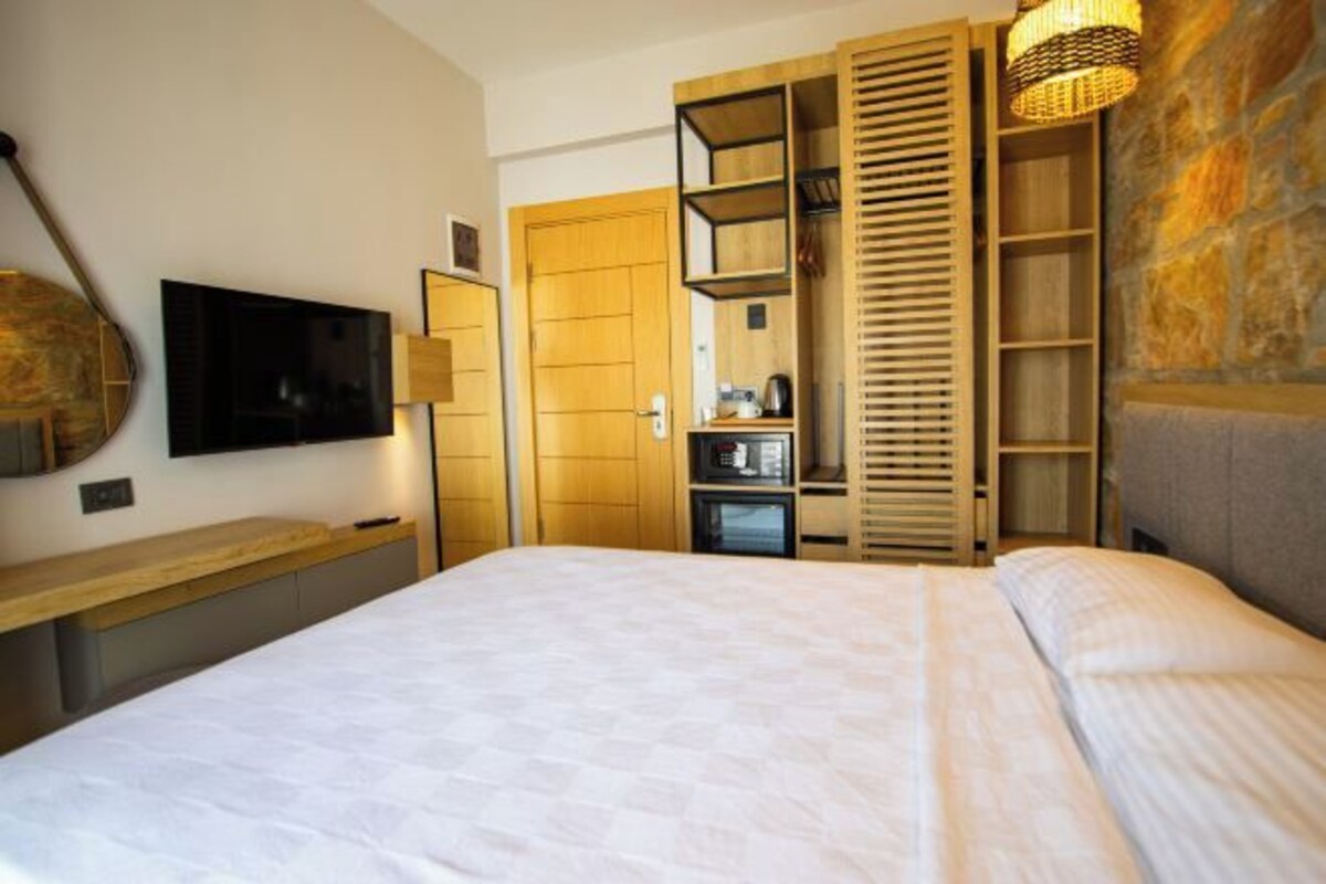 Un dormitorio moderno con una cama grande, un televisor montado en la pared y estantes empotrados de madera con un espejo.