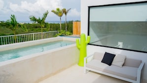 A modern balcony with a pool, a white sofa, and a large window overlooking a tropical landscape. - Siaan Betine 4br Deluxe PDC  (Playa del Carmen)