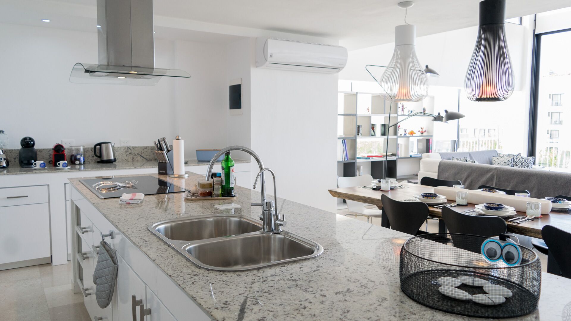 A modern kitchen with a double sink, stainless steel appliances, and a dining area with a table and chairs.