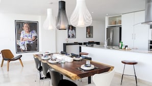 A modern kitchen with a wooden dining table, black and white pendant lights, and a large framed picture on the wall. - Siaan Betine 4br Deluxe PDC  (Playa del Carmen)