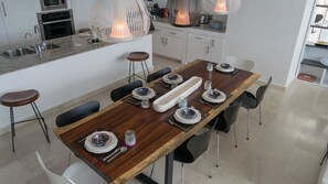Una cocina moderna con una mesa de comedor de madera dispuesta para seis personas, equipada con taburetes de bar.