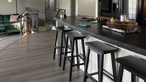 Una cocina moderna con una isla grande, taburetes de bar, un refrigerador y un microondas.