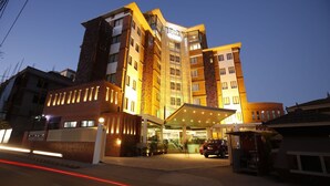 A multi-story hotel with a modern architectural design, featuring a prominent entrance with a covered walkway and a parking area in front. - Platinum Hotel and Spa (Kathmandu)