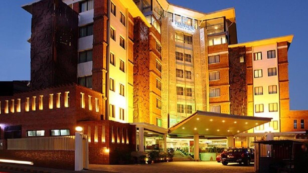Un hôtel à plusieurs étages, doté d’une entrée imposante et d’un parking couvert.