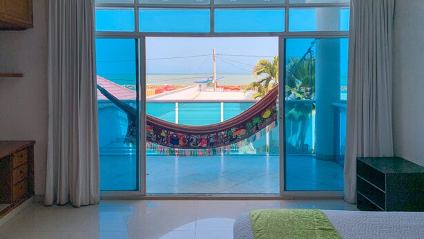 Ein Zimmer mit einer großen Schiebeglasdoor, die auf einen Balkon mit einer Hängematte führt.