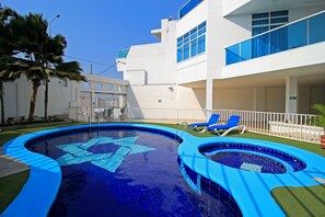 A swimming pool with a star-shaped design, surrounded by a white building with blue windows and a balcony. - Hotel Abi Inn By GEH Suites (Cartagena)