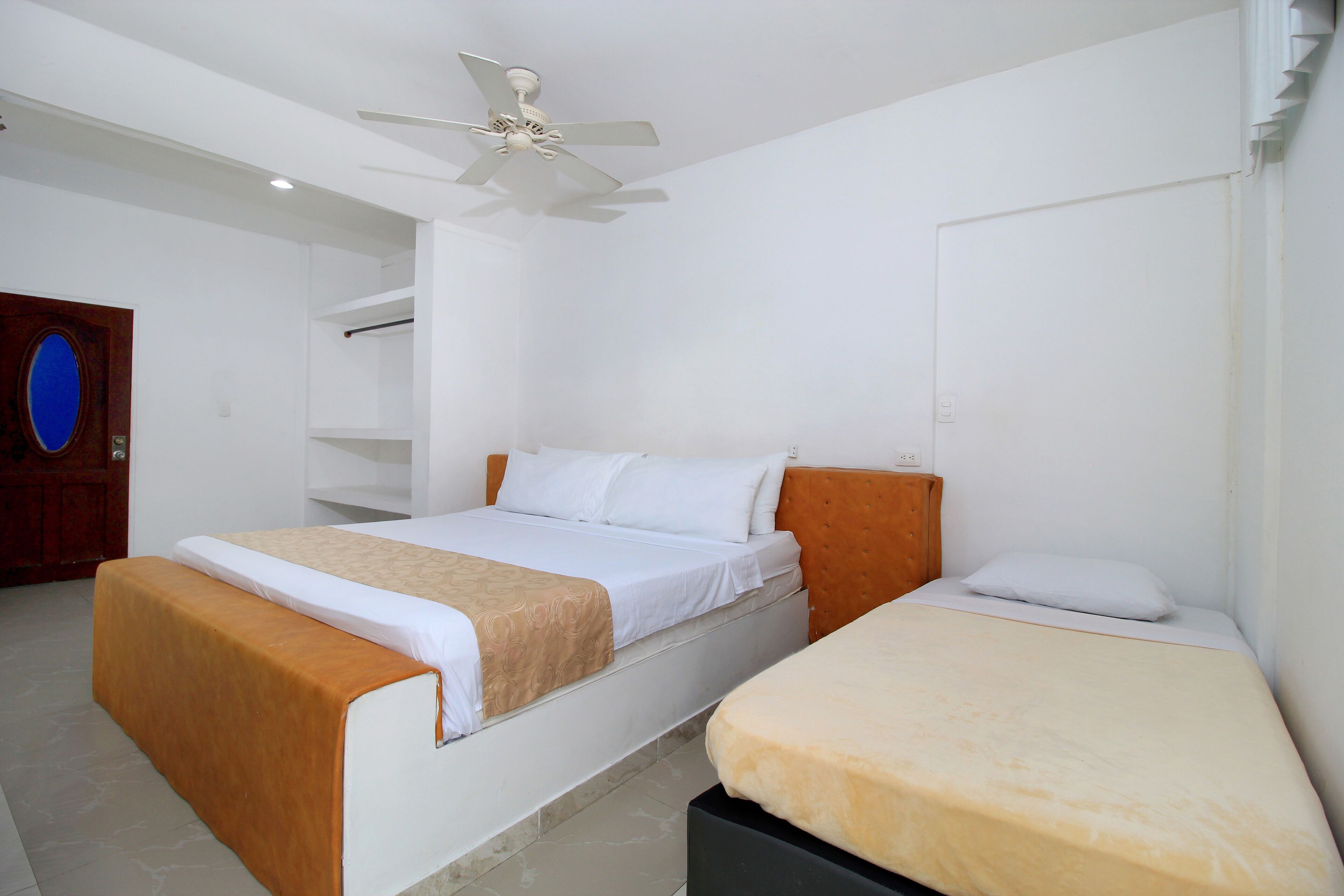 A bedroom with two beds, a ceiling fan, and a wooden door.