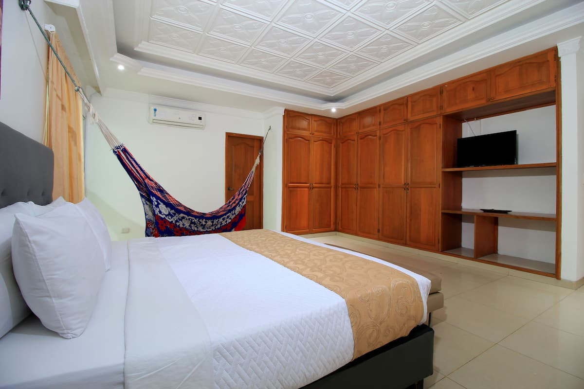 Un dormitorio con cama, hamaca, armarios de madera y televisor.