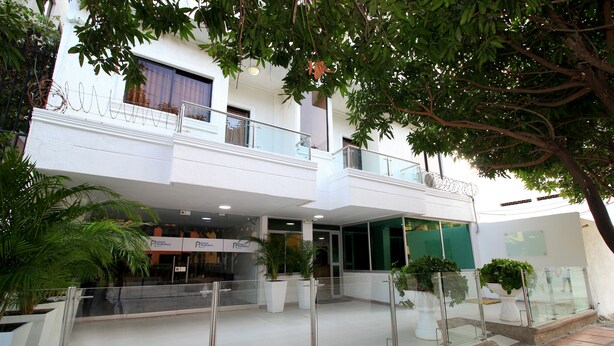 A hotel lobby with a glass railing, potted plants, and a sign for the R Hotel. - Hotel Rodadero Inn By GEH Suites (Santa Marta)