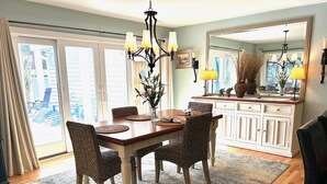 A dining room with a wooden table, woven chairs, and a chandelier. - BY THE BAY (Annapolis)