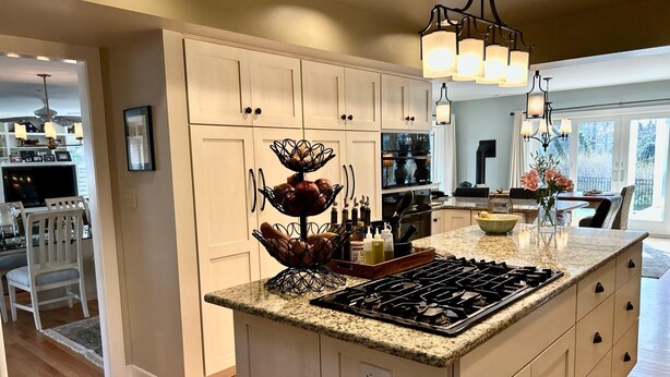 A modern kitchen with white cabinetry, a granite countertop, a gas stove, and a dining area with white chairs. - BY THE BAY (Annapolis)