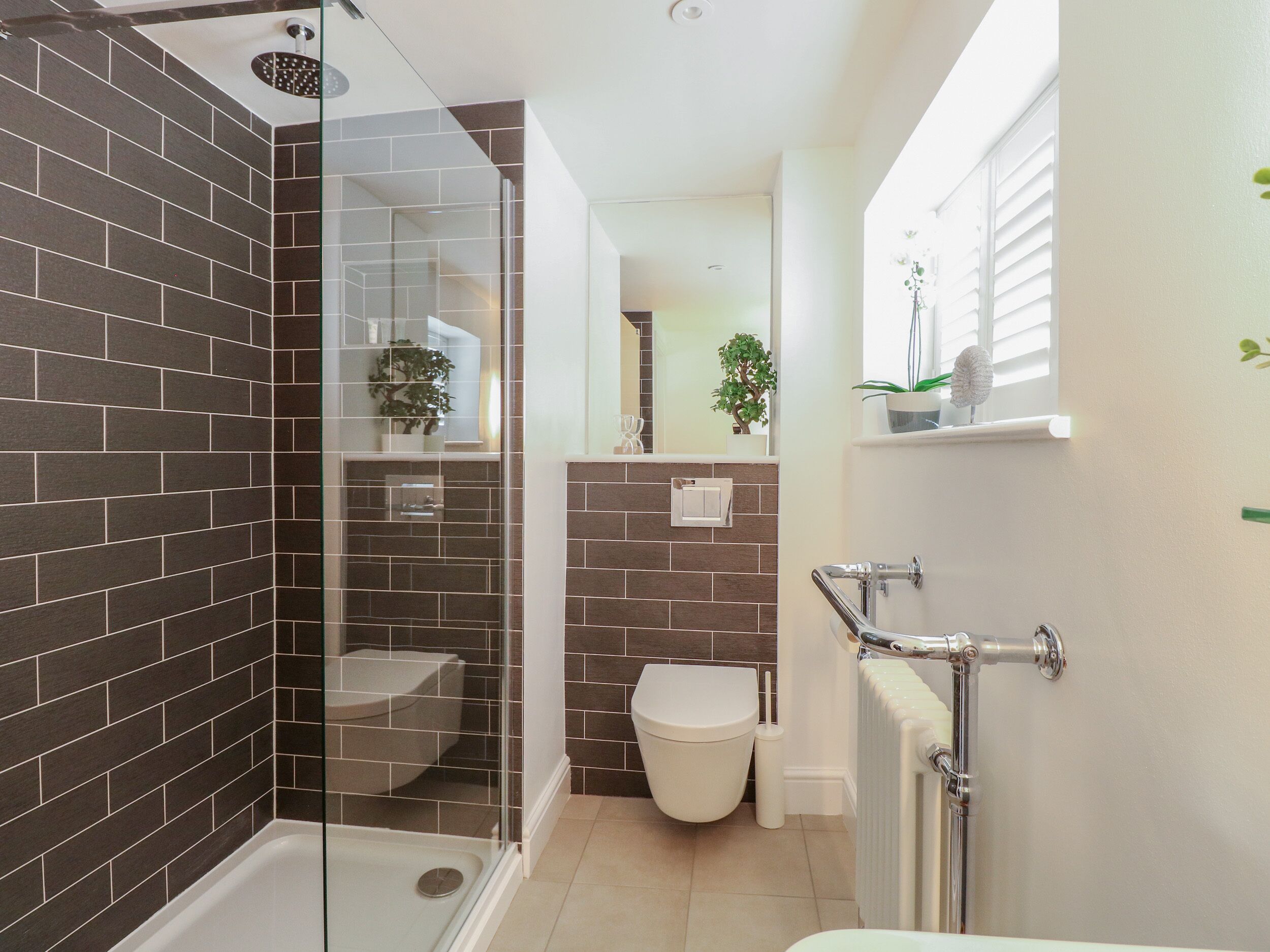 Een moderne badkamer met een douchekabinet van glas, een toilet en een bad.
