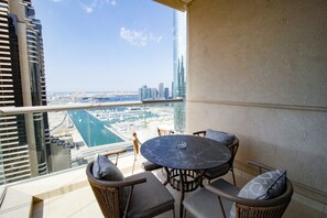 A balcony with a round table and chairs, overlooking a marina and cityscape.