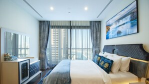 Una habitación de hotel moderna con una cama grande, una mesita de noche, un aparador y un ventanal con cortinas.