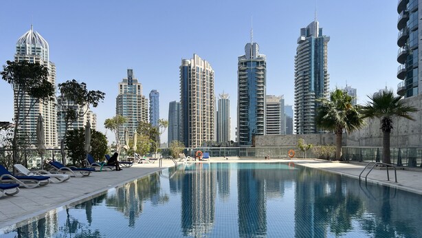 Una piscina con sillas de descanso y un paisaje urbano al fondo.