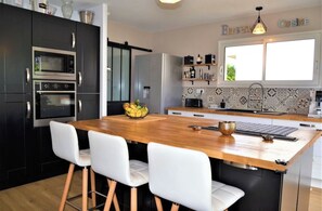 Eine moderne Küche mit einer Holztheke, weißen Stühlen und eingebauten Geräten.