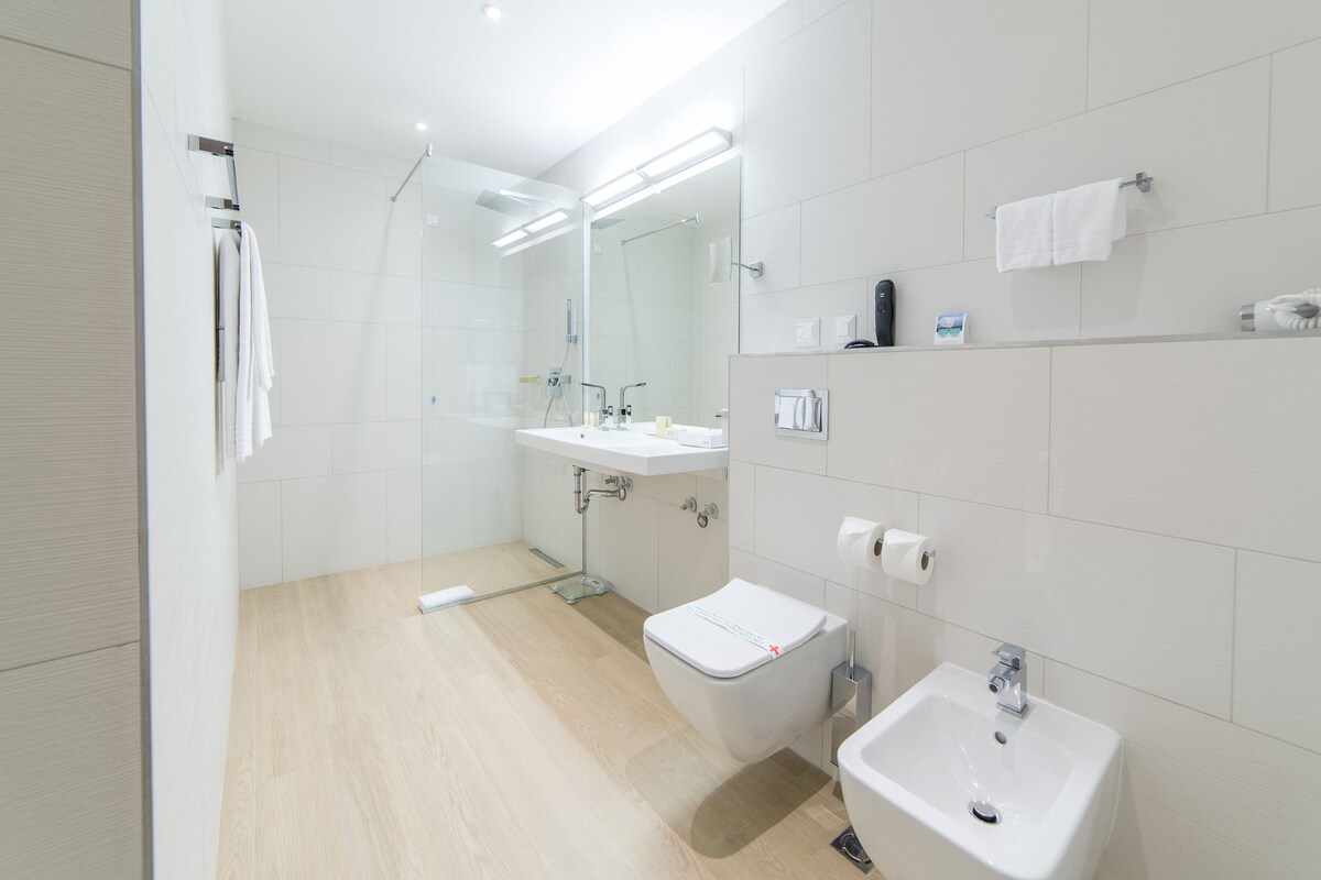 A modern bathroom with a shower, toilet, sink, and bidet.