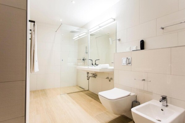 A modern bathroom with a shower, toilet, sink, and mirror.