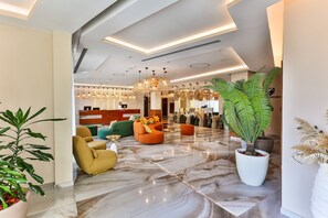 A modern hotel lobby with a marble floor, seating areas, and a reception desk. - Hotel Tq Plaza (Budva)