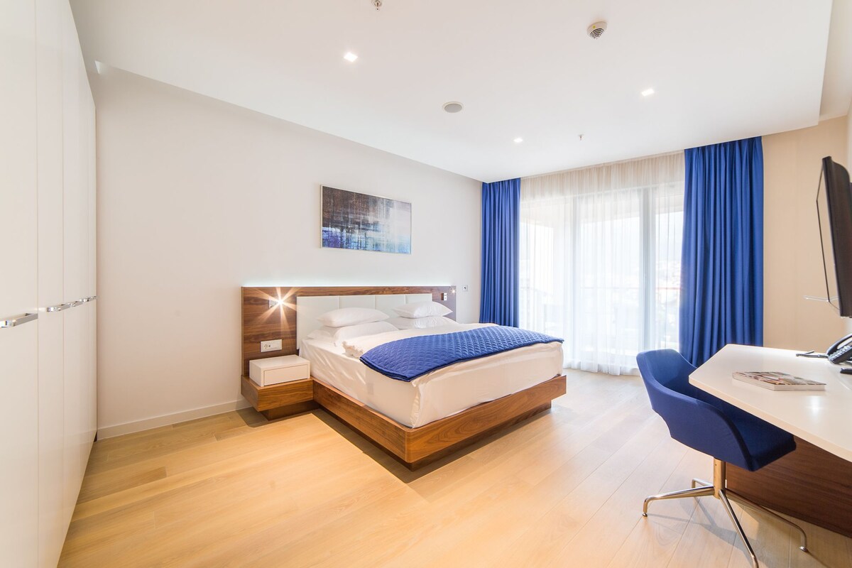 A modern hotel room with a wooden bed, a desk, and a chair.