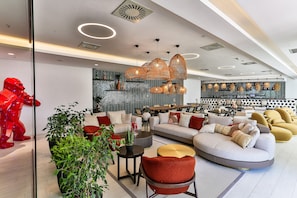 A modern interior with a sectional sofa, red chairs, and a dining area with a black and white patterned wall.