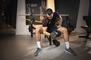 A gym with exercise equipment, a motivational poster, and a person performing a seated exercise. - Hotel Tq Plaza (Budva)