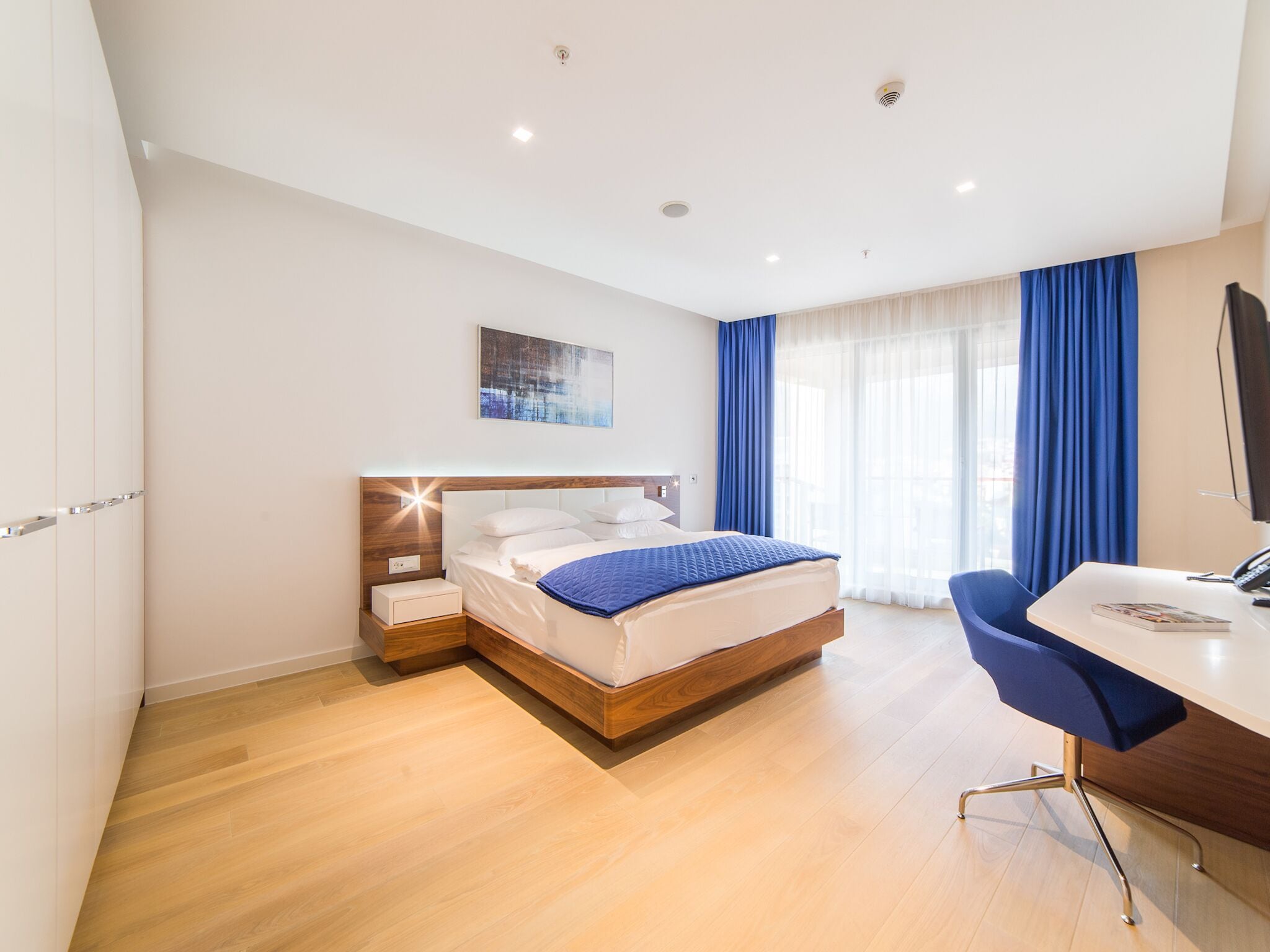 Ein modernes Hotelzimmer mit einem hölzernen Bett, einem Schreibtisch und einem Stuhl.
