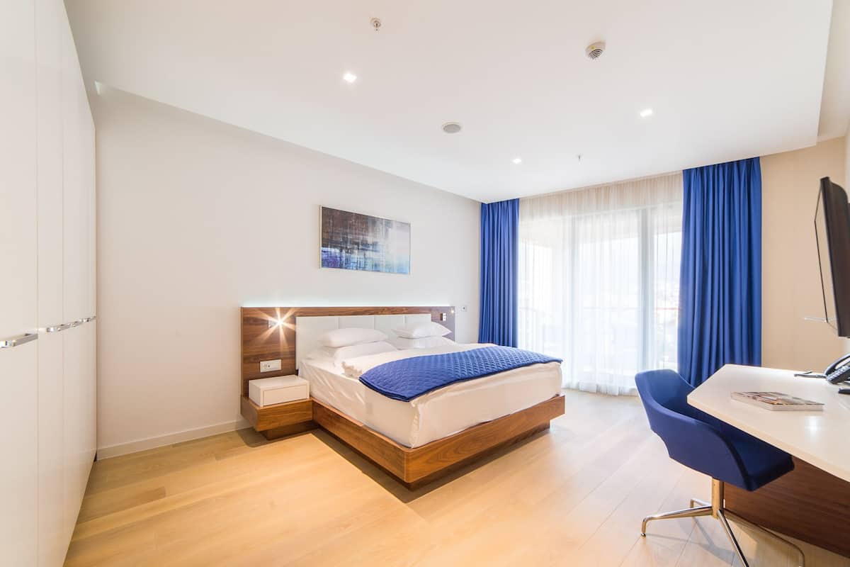 Une chambre d’hôtel moderne avec un lit en bois, un bureau et une chaise.