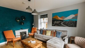 Un soggiorno con una parete verde acqua, un camino, un divano e un tavolino da caffè.