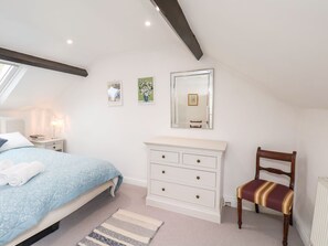 A bedroom with a bed, a dresser, a chair, a mirror, and artwork on the wall. - Riseholme (Scarborough)