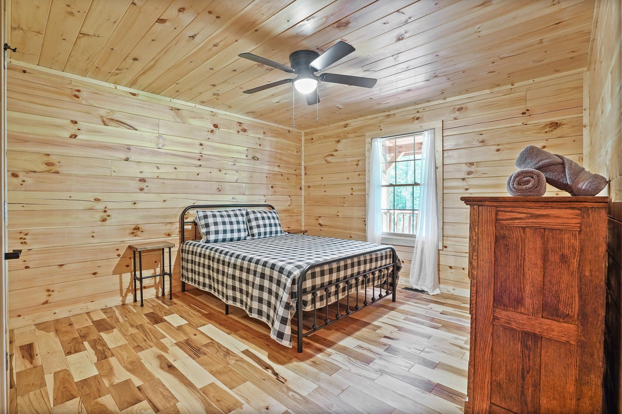 A wooden-paneled room with a bed, a small table, and a wardrobe.