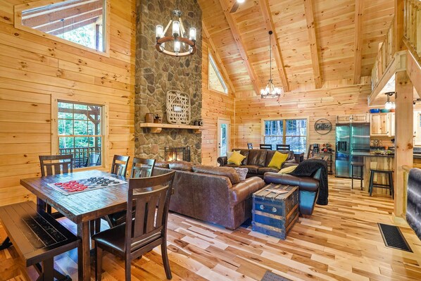Cozy cabin-style interior with a high ceiling, stone fireplace, and comfortable seating area.