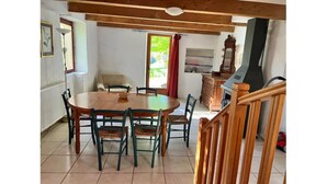 A dining area with a wooden table and chairs, a kitchen area with a grill, and a staircase with wooden railings.