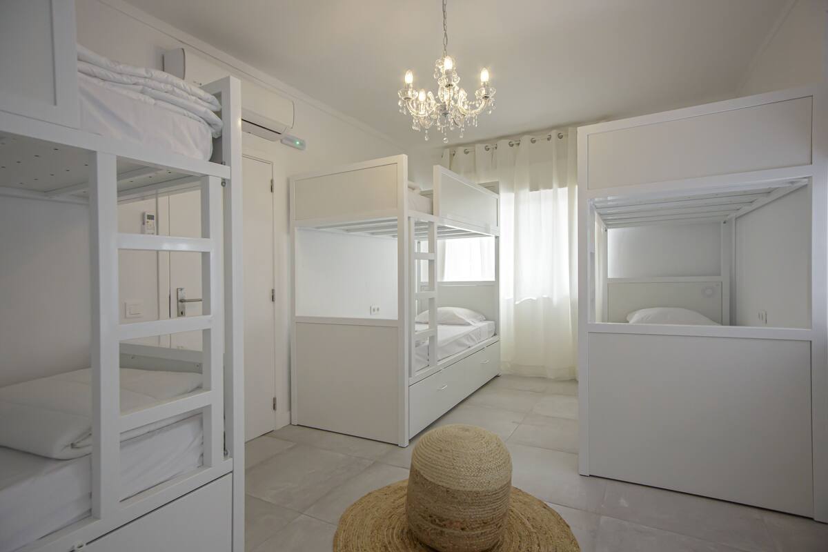 A bedroom with bunk beds, a chandelier, and a woven basket.