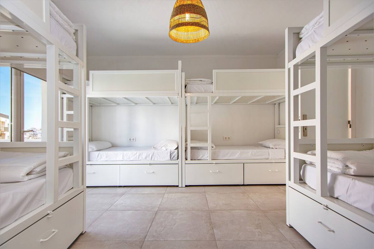 A room with bunk beds, a large window, and a hanging light fixture.