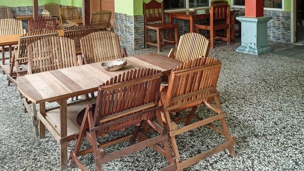 A room with wooden tables and chairs, a tiled floor, and green walls. - OYO 91768 Hotel Tanjung Permai (Tanjung Selor)