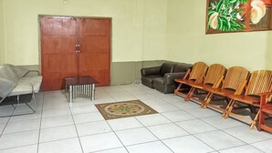A waiting area with a sofa, chairs, a coffee table, and a door. - OYO 91768 Hotel Tanjung Permai (Tanjung Selor)