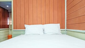 A bed with white linens in a room with wooden panel walls. - OYO 91768 Hotel Tanjung Permai (Tanjung Selor)