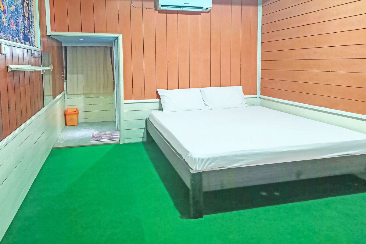 A room with a bed, a small door, and a green carpet.