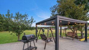An outdoor patio with a grill, swing seats, and string lights. - Red Roof Inn & Suites Carrollton, Ga-west Georgia (Carrollton)