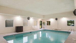 An indoor swimming pool with clear water, a tiled floor, and a few chairs and a small table. - Red Roof Inn & Suites Carrollton, Ga-west Georgia (Carrollton)