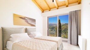 Une chambre avec deux lits, une grande fenêtre donnant sur un paysage montagneux et un plafond en bois.