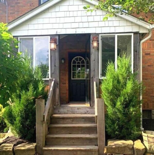 Stylish single-story home with a brick facade, featuring a welcoming entrance and a wooden staircase.