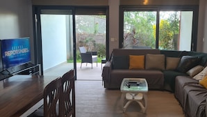 Una sala de estar con un sofá, una mesa de centro y un televisor sobre un mueble.