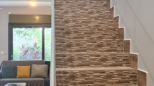 Una escalera de diseño moderno que lleva a un balcón en el segundo piso con plantas en macetas.
